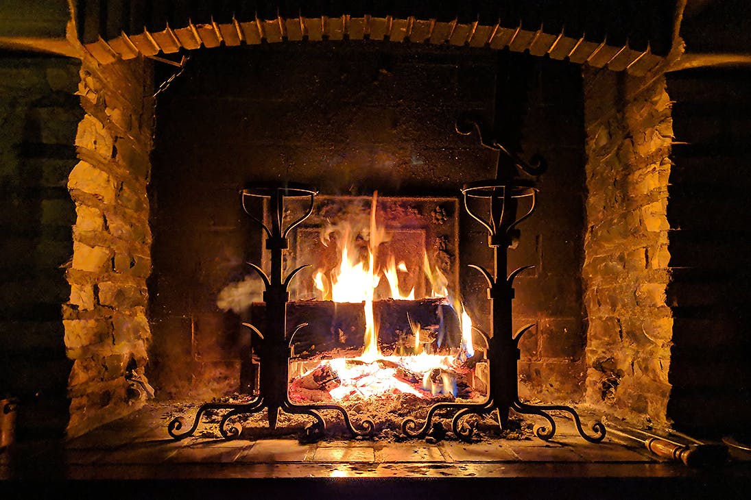 A cosy looking hearth with a roaring fire.